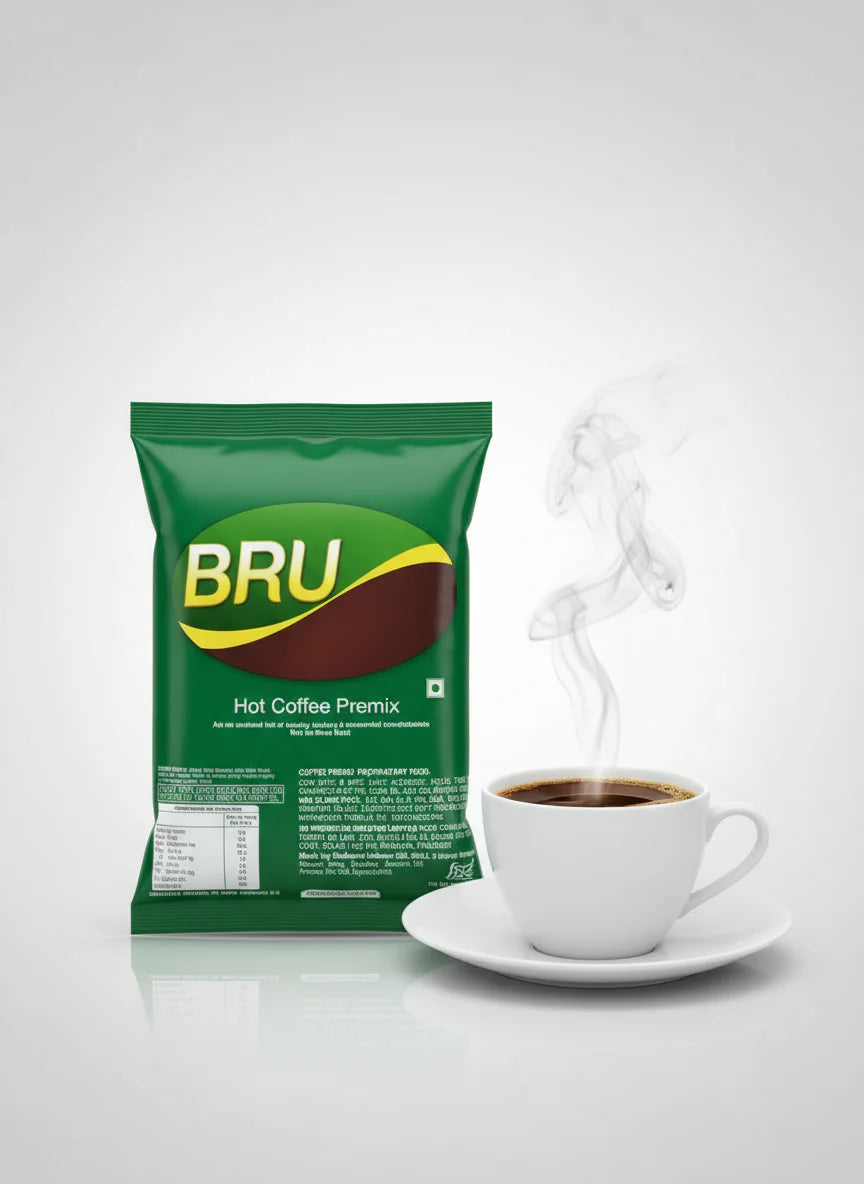 Bru coffee premix 1kg green pack next to steaming cup of hot coffee on white saucer
